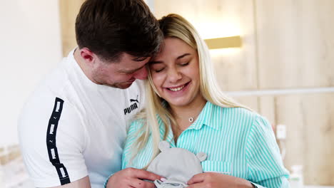 young people are happy expecting their future baby. smiling couple look at kid's clothes, embracing and kissing each other.