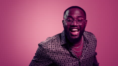 happy afro guy singing indoors. handsome male person dancing on pink background