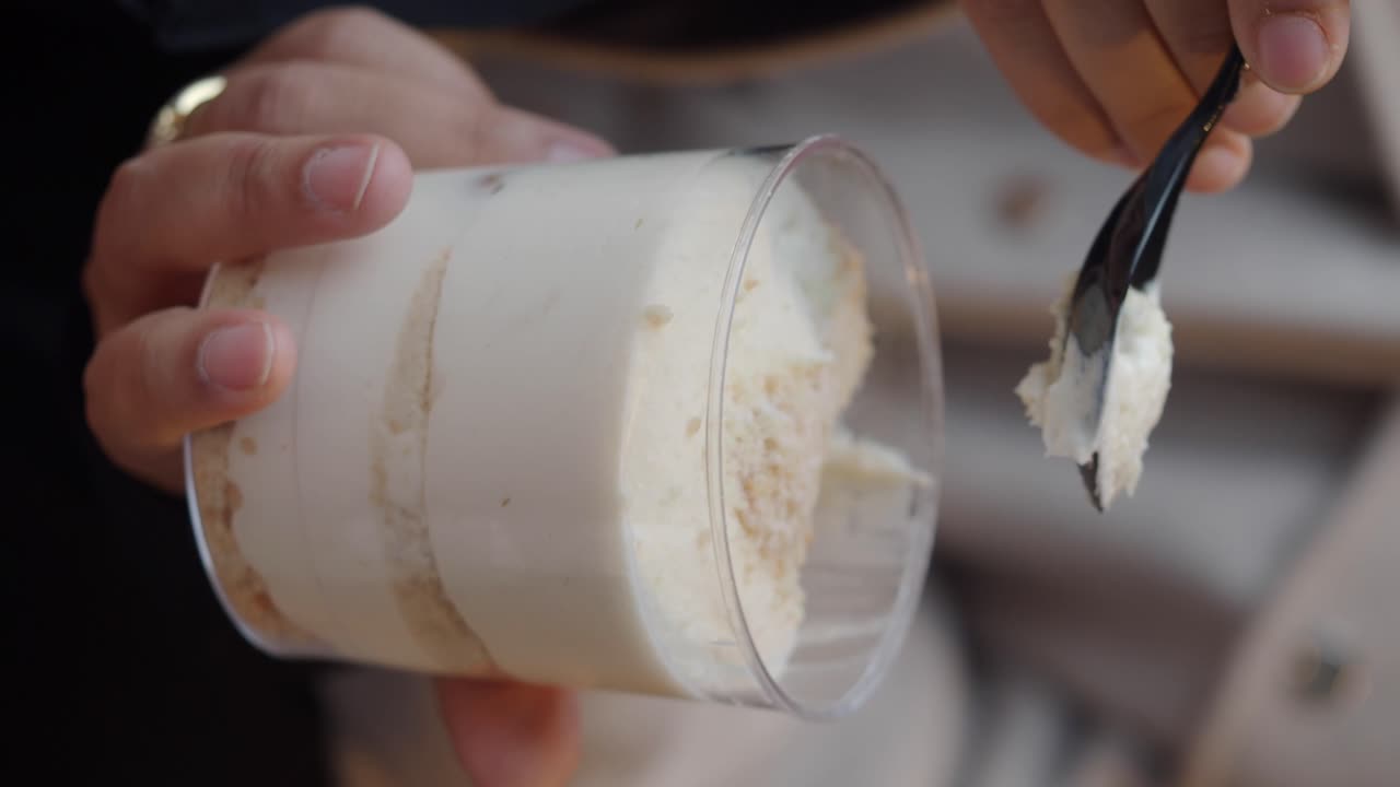 Person eating layered dessert with a spoon