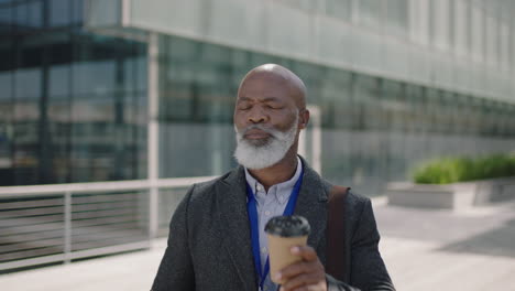 portrait of mature african american businessman ceo relaxed using smartphone drinking coffee enjoying urban outdoors on lunch break in city