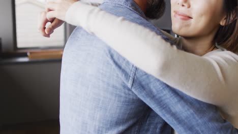 pareja feliz diversa vestida con ropa casual abrazándose juntos en la cocina