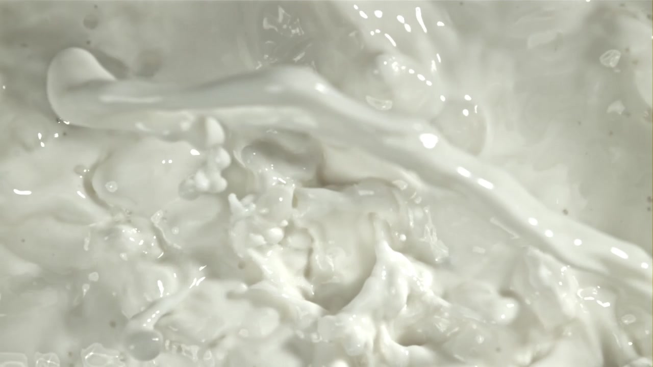 Primo piano di latte bianco che schizza e si versa al rallentatore