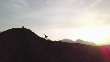 One-man-waves-into-the-camera,-as-the-drone-rises-the-sun-shines-right-in-the-camera