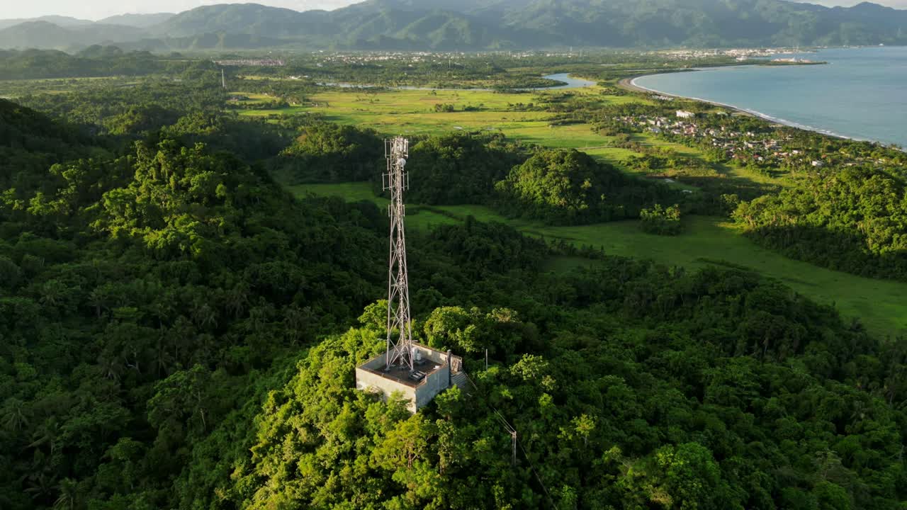 Hyperlapse of phone telecommunications tower on lush hilltop during golden hour at province Catanduanes, Philippines - aerial orbit