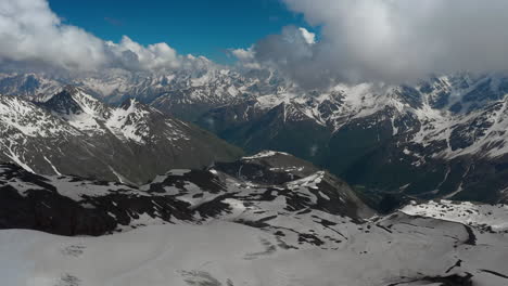 air flight through mountain clouds over beautiful snow-capped peaks of mountains and glaciers.