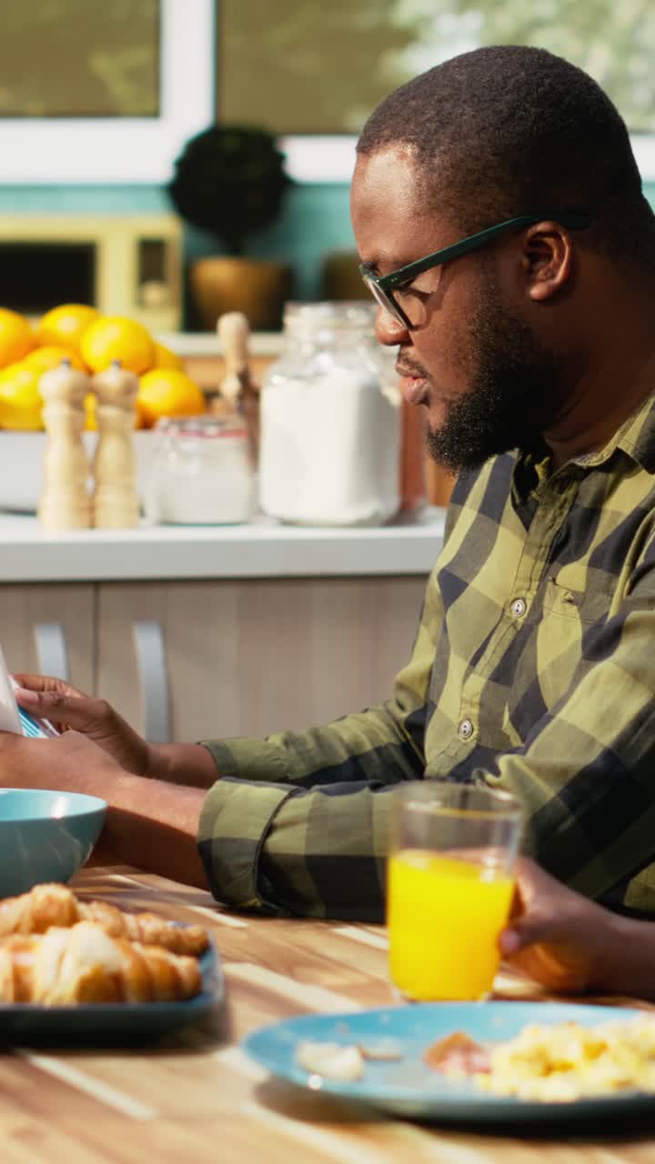 Vertical Video African american distracted father studying some papers at breakfast