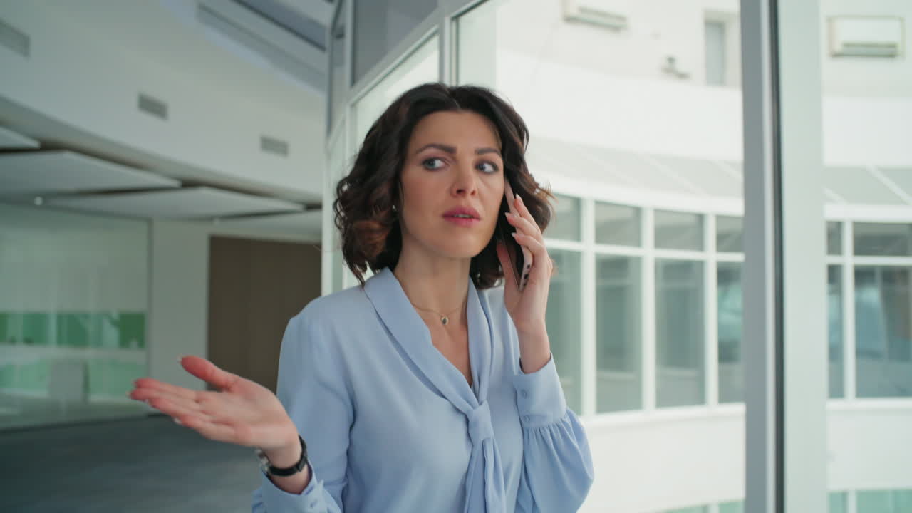 Elegant woman talking mobile phone walking office corridor closeup. Serious lady