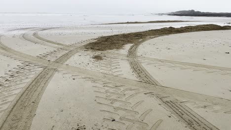 Fogy-morning-with-tractor-tracks-on-a-sandy-beach-in-Ireland