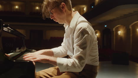 relaxed man playing piano in empty concert hall