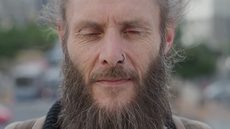 close up portrait mature bearded hippie man looking up pensive homeless guy living independent urban lifestyle in city wearing nose ring wrinkles aging