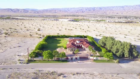 a dramatic aerial reveals a large mansion in miles of lonely desert