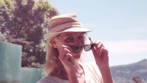 rubia atractiva con sombrero quitándose las gafas de sol