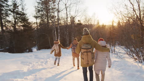 amigos caminando en el bosque nevado al atardecer