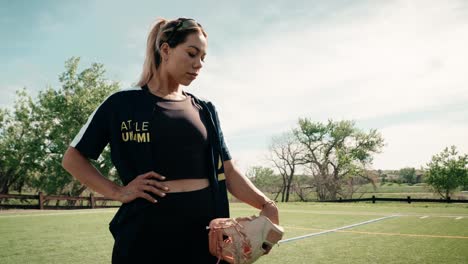 Hermosa-Atleta-Femenina-De-Softbol-Adopta-Una-Pose-Dramática-Parada-Mientras-Sostiene-Su-Guante-Al-Lado-De-Su-Cuerpo-En-Forma