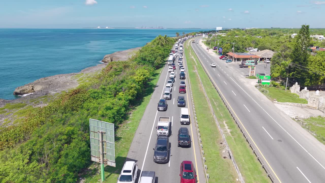 Drone flying over traffic jam on Las Américas Highway next to Caribbean coast, Dominican Republic. Aerial forward