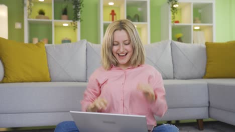 una mujer joven mirando la computadora portátil en su regazo se regocija.