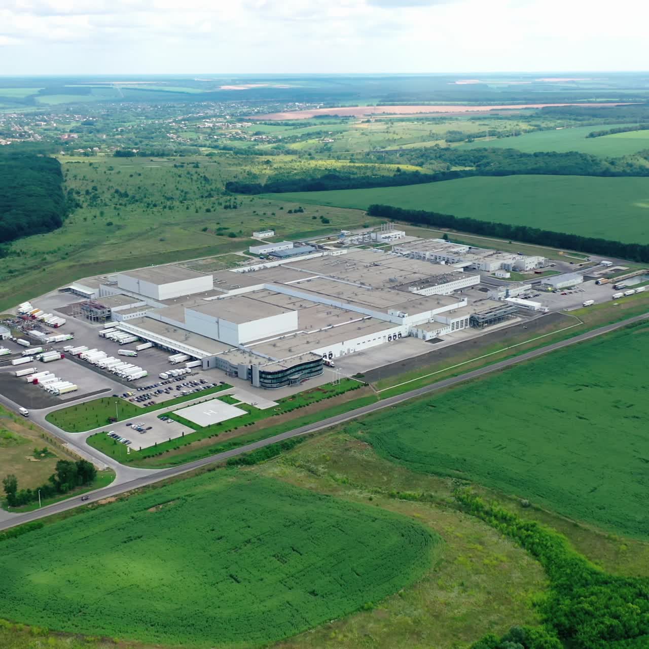 Modern factory in rural place. Innovative complex of industrial plant on green nature background. Industrial zone on fields. Aerial view