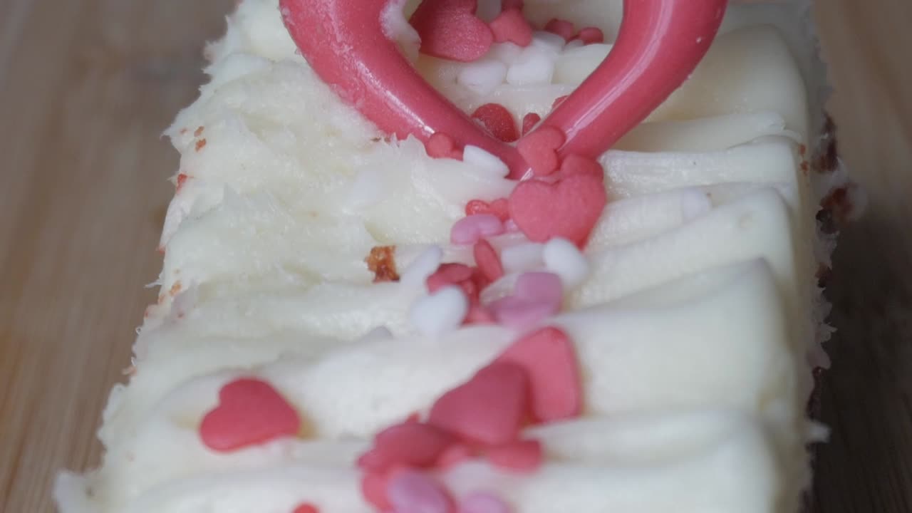 Close-up of red velvet brownie with creamy frosting and heart-shaped sprinkles
