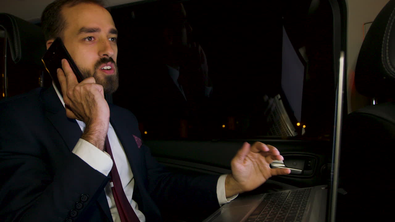 un hombre de negocios enojado gritando durante una llamada telefónica en el asiento trasero de su limusina