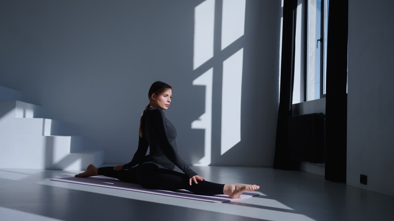 Woman doing a split yoga pose in a studio