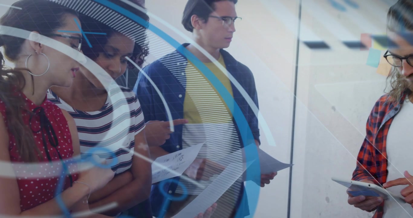 Business team reviewing diagrams on glass wall tapping tablet showing AR graphics for collaboration