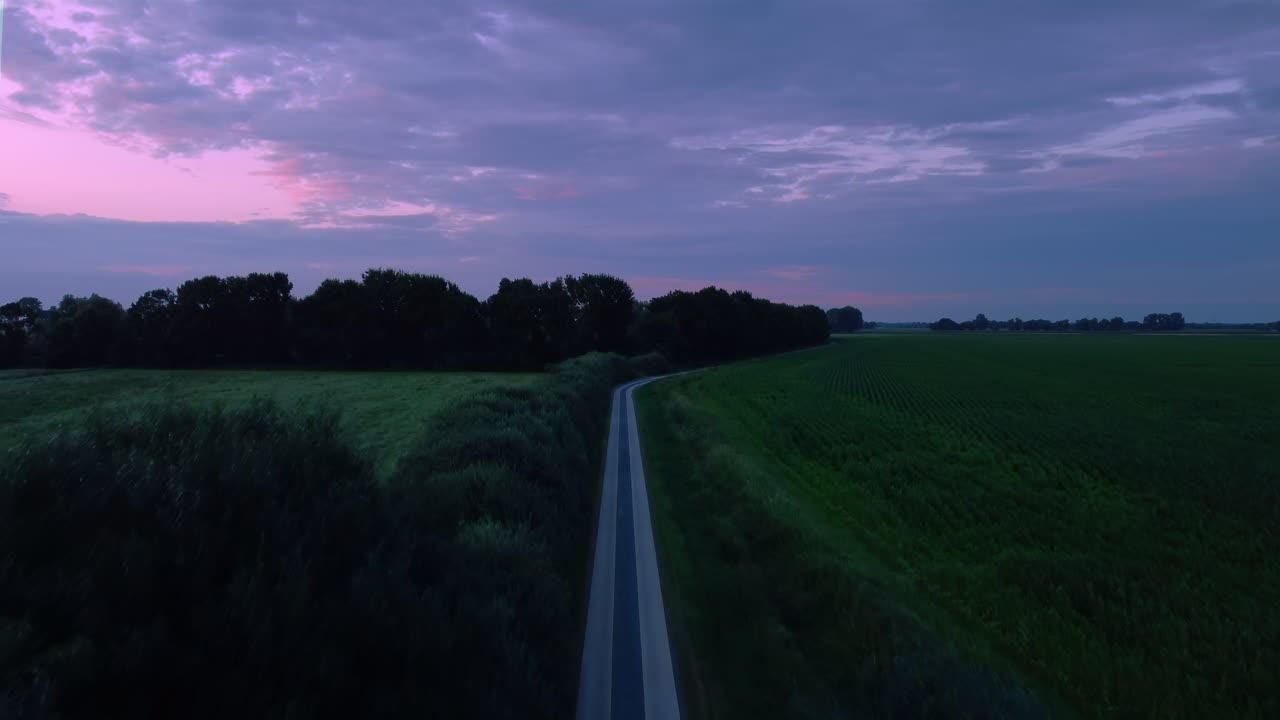 una puesta de sol atmosférica sobre una carretera rural, tiro de drones hacia arriba