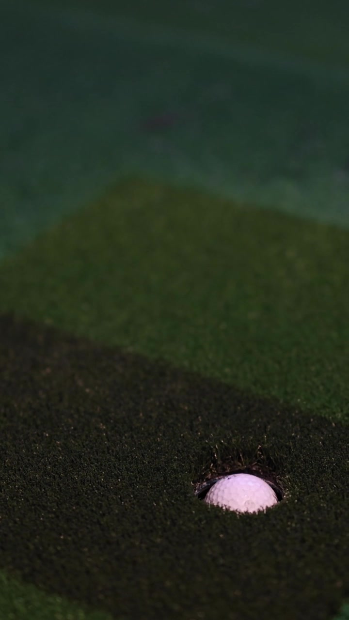 Una pallina da golf bianca viene colpita da un putter e rotola nella buca.