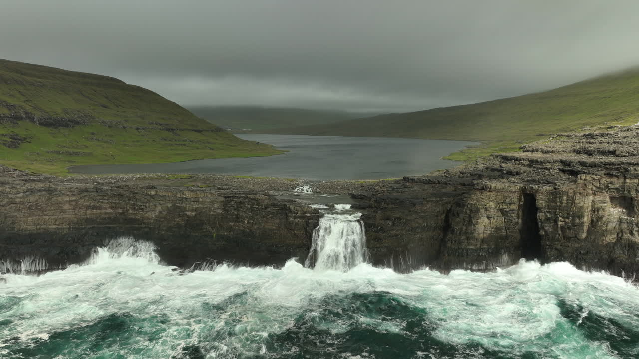 vuelo aéreo hacia el lago por encima del océano, cascada de sorvagsvatn en vagar, islas feroe en un día nublado