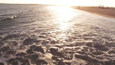 drone footage of seal beach in orange county california with ocean waves crashing into the sand