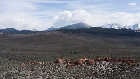 Vast-desert-landscape-with-snow-capped-mountains-and-red-rock-formations-in-california,-aerial-view