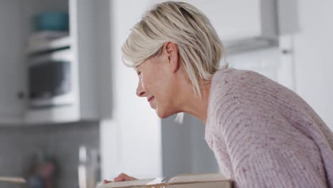 Feliz-Mujer-Caucásica-Mayor-Mudándose-De-Casa,-Desempacando-Cajas-En-La-Cocina