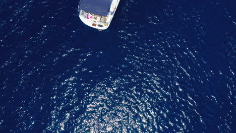 aerial: top down drone shot of a sailboat in blue sea