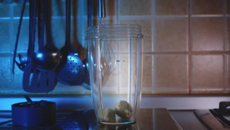 hacer un batido saludable de proteína de plátano y chocolate en la cocina, poniendo todos los ingredientes en la jarra de la licuadora