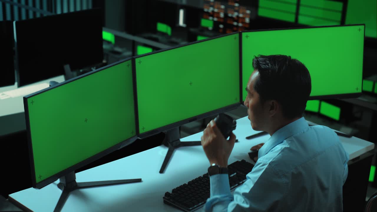 vista lateral de un hombre asiático bebiendo café y trabajando con múltiples monitores de computadora simulados en la oficina