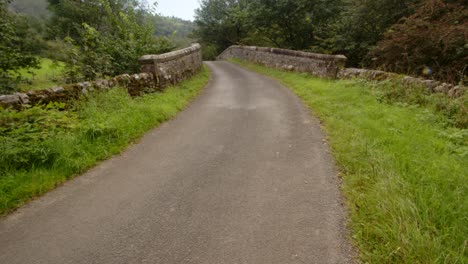 wide shot road going over the old leek road stone bridge near wetton mill