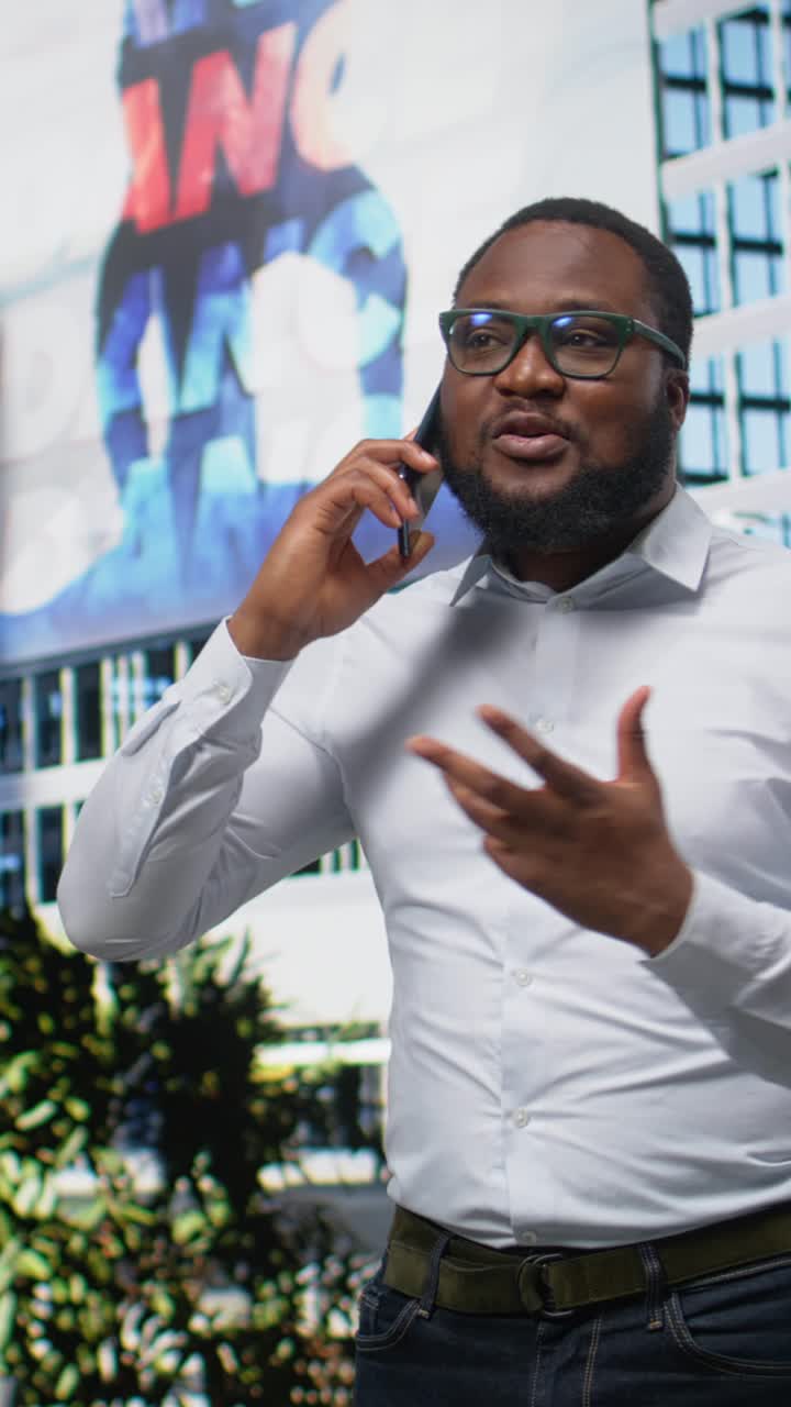 Vertical Video African american man chatting on a phone call through urban avenue