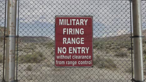 high quality 3d cgi render with a smooth dollying-in shot of a chainlink fence at a high security installation in a desert scene, with a military firing range no entry sign