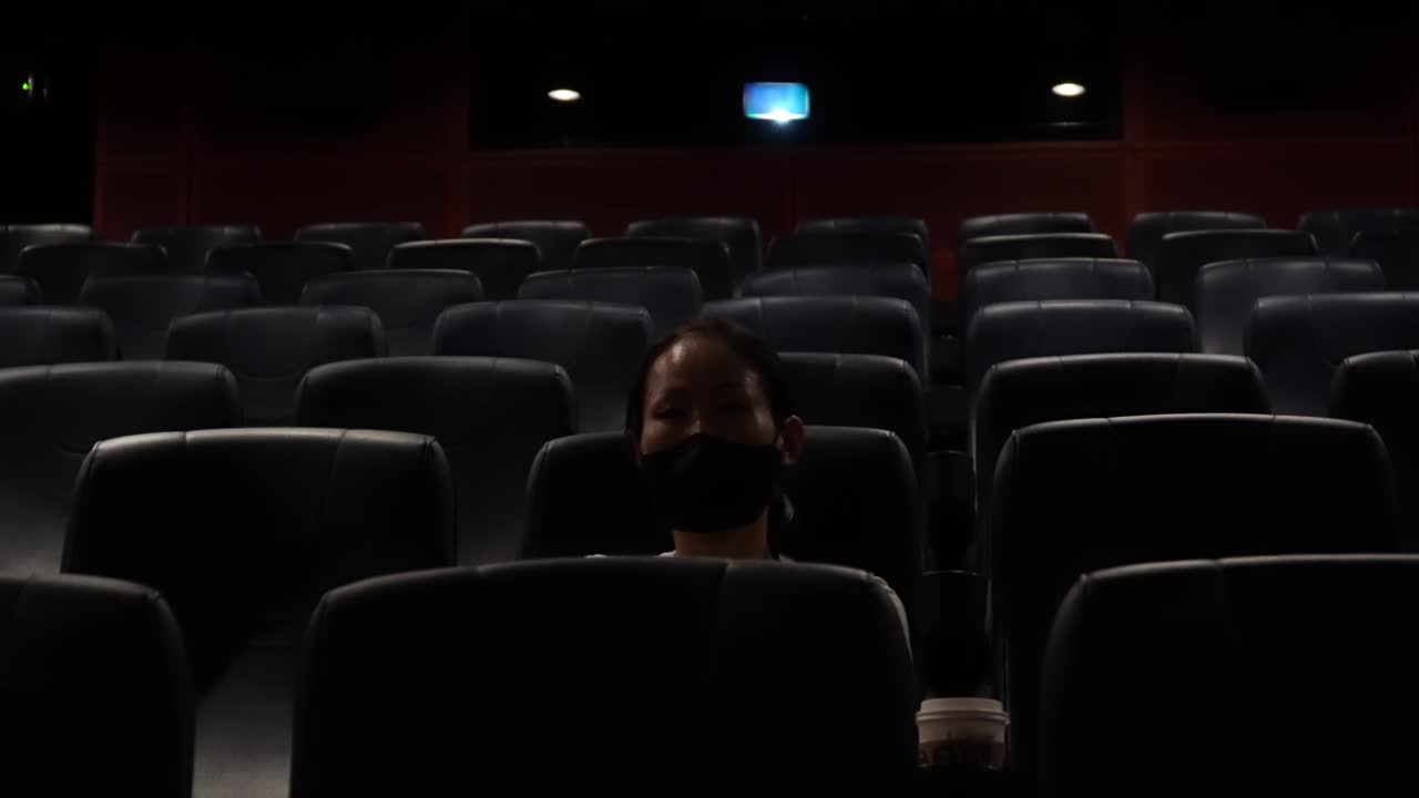 Korean Woman Sitting Alone In The Dark Cinema with all Seats Empty And Watching Movie After A Long Day with Nobody Around during Covid-19 Coronavirus Pandemic in South Korea wide