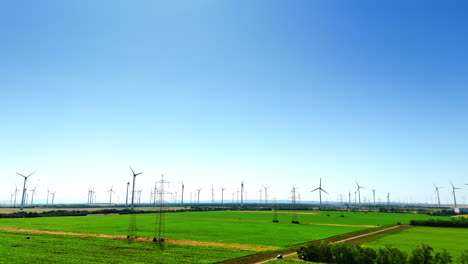 turbines produce clean energy. expansive green fields host numerous wind turbines under a clear blue sky, producing renewable energy