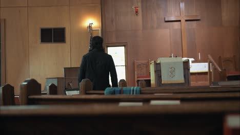 Christian-pastor-in-black-suit-walking-in-church-sitting-in-pew-in-cinematic-slow-motion