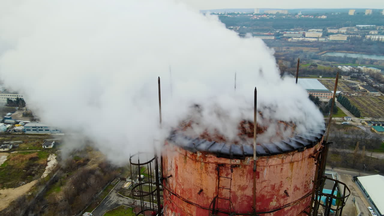 Vista aerea da drone di una centrale termica con fumo che esce dal tubo. Edifici, strade e alberi spogli sullo sfondo. Tempo nuvoloso. Chișinău, Moldavia