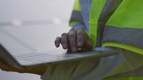 Woman-in-a-green-visibility-vest-and-hard-hat-works-on-a-laptop