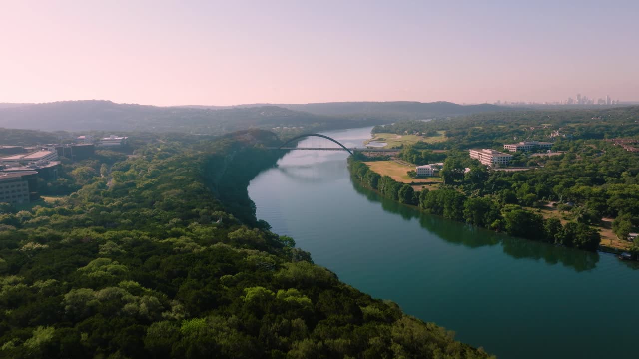 inclinación aérea sobre el cinturón verde del lago austin para revelar el puente pennybacker 360 durante el brumoso amanecer de verano en austin, texas