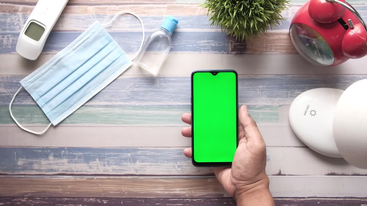 teléfono inteligente con pantalla verde y suministros de protección en un escritorio