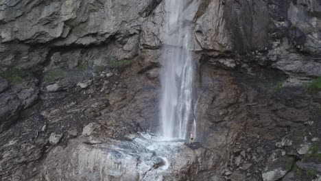 El-Hombre-Está-Parado-Cerca-De-La-Cascada-Almenbachfall-Berner-Oberland-Suiza-Vuelo-De-Drones