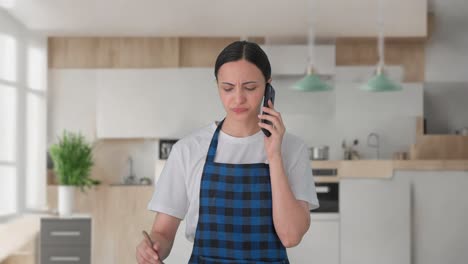 indian housewife talking on call while making food