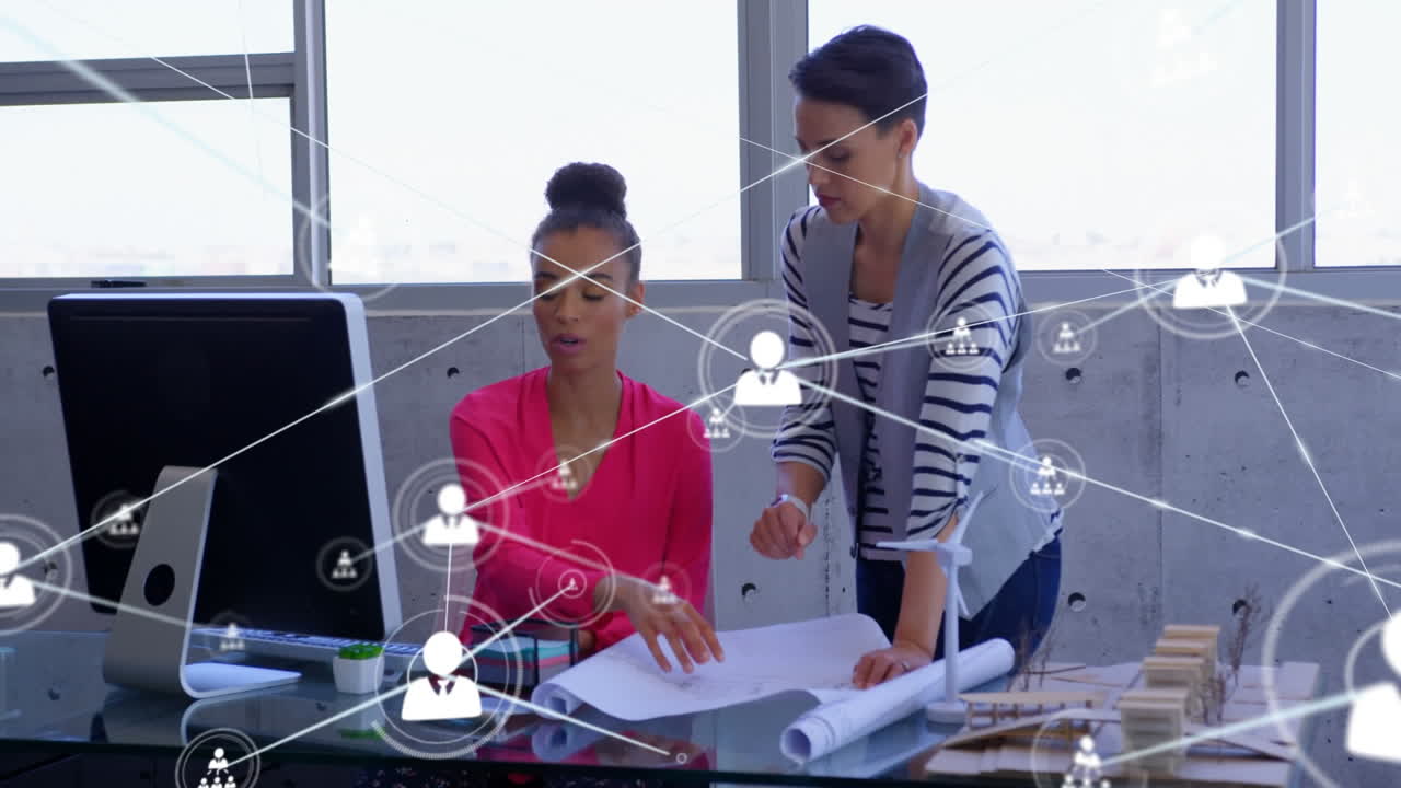 animación de una red de iconos digitales sobre dos mujeres diversas discutiendo un plan en la oficina