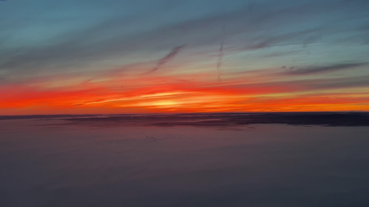 Sonnenaufgang über Deutschland bei Frankfurt aus einem Jet-Cockpit nach dem Start, mit einem intensiv roten Himmel an einem kalten Wintermorgen.
