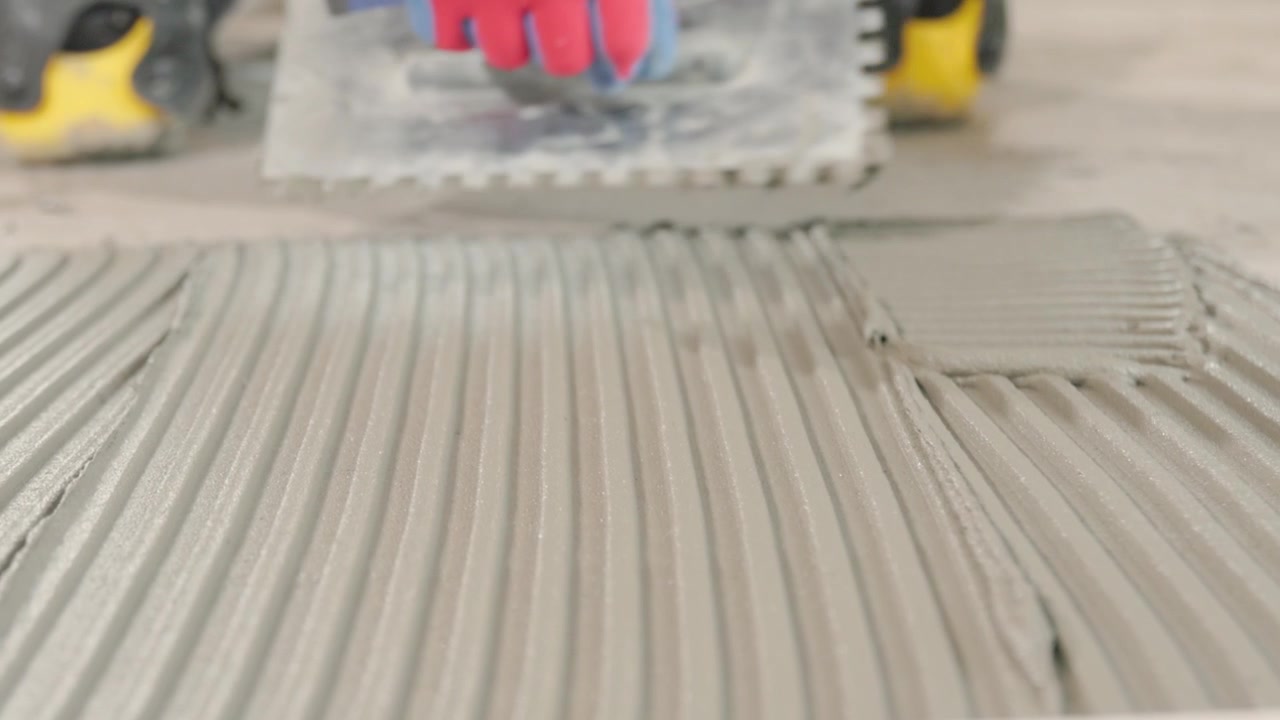Spreading tile adhesive before installing tiles on the floor. Contractor building a house.