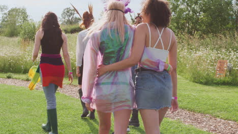 rear view of excited young female friends walking through music festival site